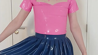 Putting on blue spandex microskirt over rosy rubber maid dress and stockings, layers